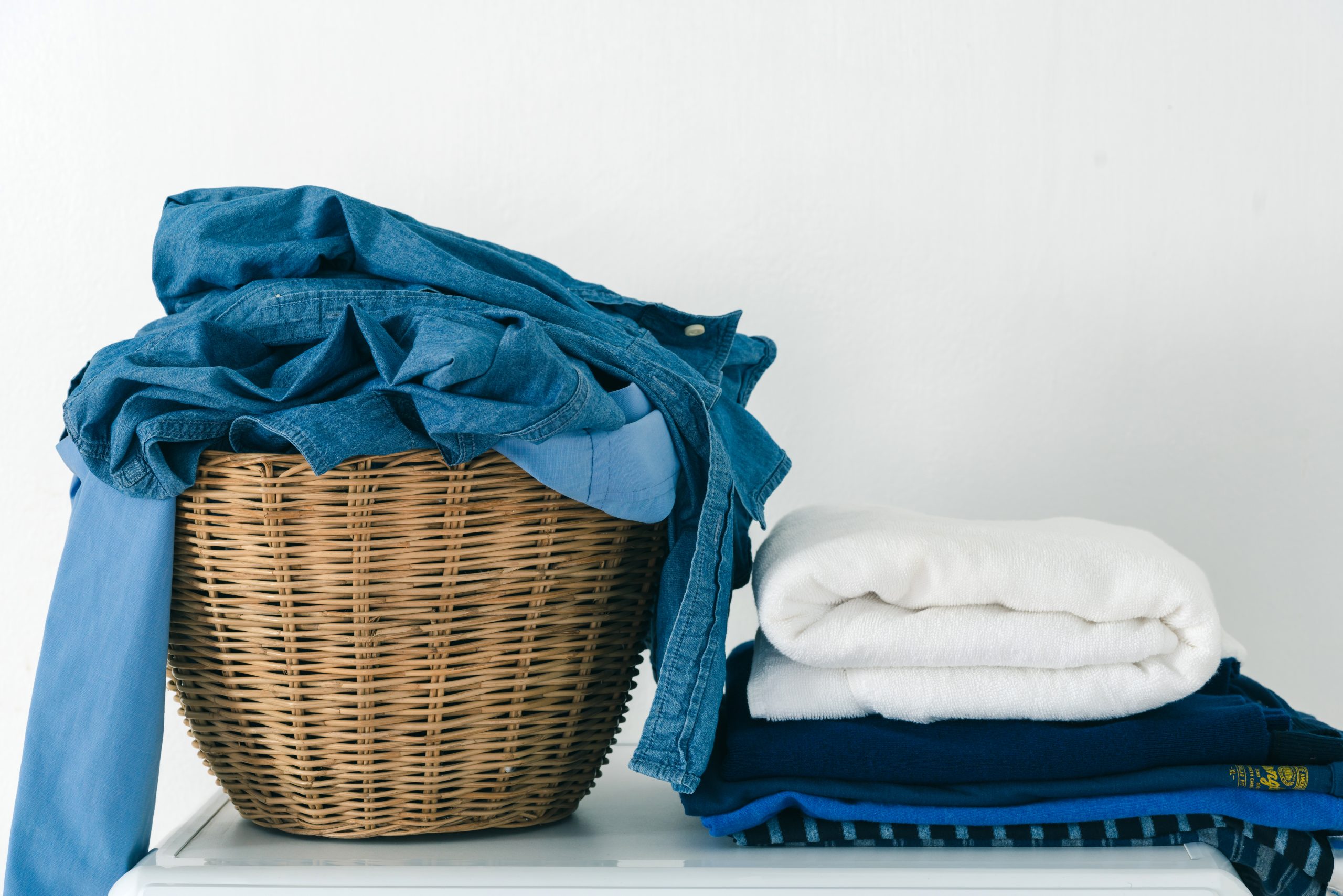 Close up clothes in basket and pile fabric on washing machine with white background. Laundry concept.